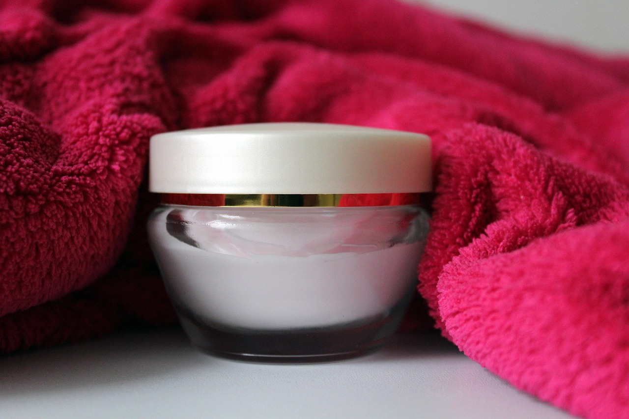 A jar of face cream resting on a soft pink towel