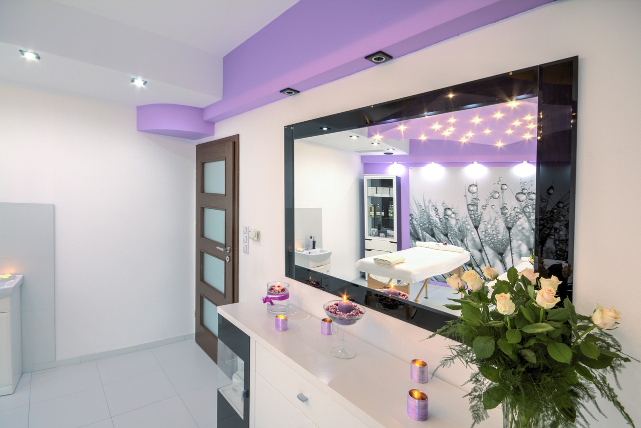 A bright treatment room with a mirrored wall, treatment bed and flowers